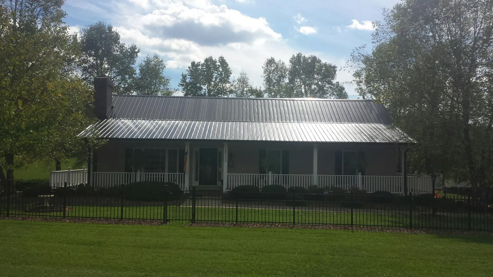 Gray metal roof on a brick ranch with a full width front porch — Gutter Guard Installation work by our crew in Hollister