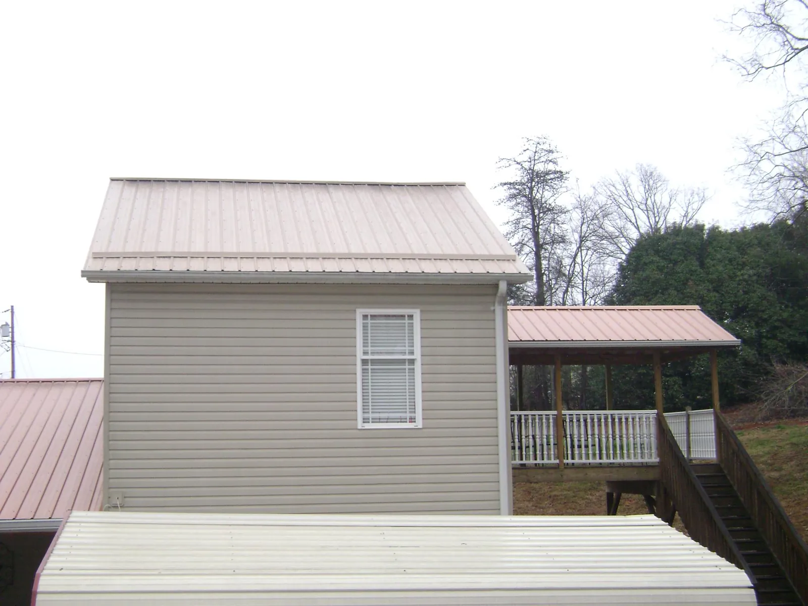 Tan metal roofs on a two story addition and attached porch, from a Roof Replacement job in Hollister